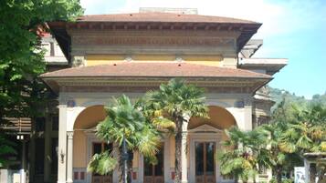 Un edificio in stile classico con una cupola centrale e finestre ad arco, circondato da palme.