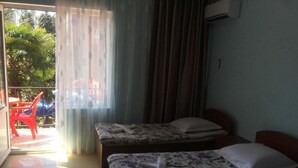 A hotel room with two beds, a balcony with a red chair, and a view of greenery outside. - Gio 350 (Kobuleti)