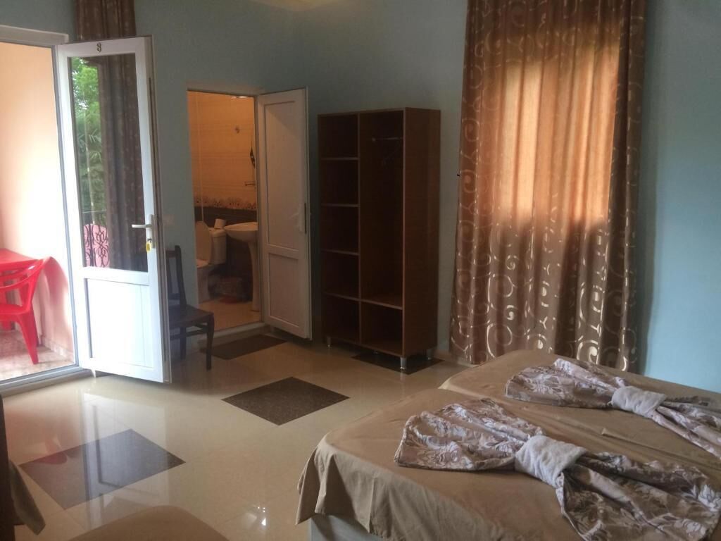 A hotel room with a bed, a wardrobe, a door leading to a balcony, and a red chair.