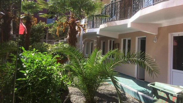 A courtyard with a pool, palm trees, and a building with balconies. - Gio 350 (Kobuleti)