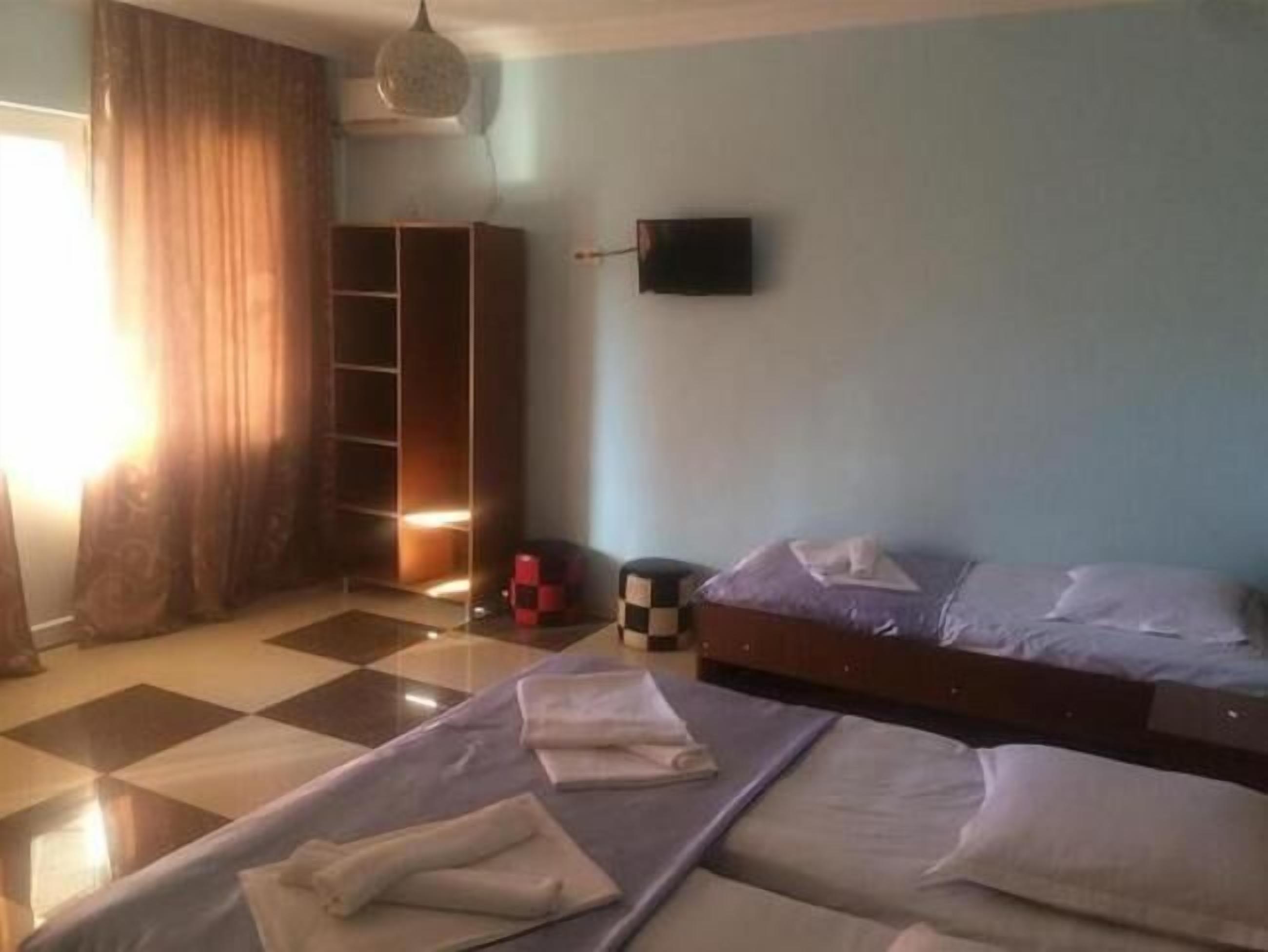 A hotel room with two beds, a wardrobe, a television, and a checkered floor.