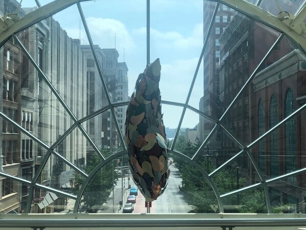 A large glass structure with a geometric design, reflecting city buildings and a street.
