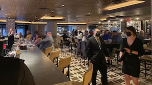 A restaurant with a patterned floor, tables, and chairs, and people dining. - 360° TERRACE VIEW KING BEDS SELF CHECK-IN WIFI W/D (Indianapolis)