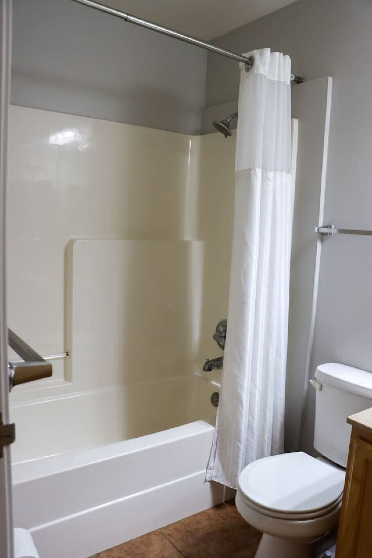 A bathroom with a shower, toilet, and bathtub.