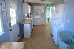 A compact kitchen with white appliances, a wooden countertop, and a light blue wall.