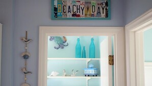 Una habitación con una pared azul claro, una puerta con marco blanco y un letrero encima de la puerta que dice 'BEACH DAY'.