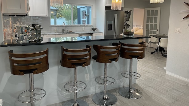 A modern kitchen with a central island, bar stools, pendant lighting, and a view of the outdoors. - Mid Century home close to beaches and downtown Dunedin. 1 block from the Trail. (Clearwater)