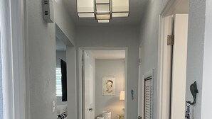 A hallway with a ceiling light fixture, a door with a keyhole, and a wall-mounted decoration. - Mid Century home close to beaches and downtown Dunedin. 1 block from the Trail. (Clearwater)