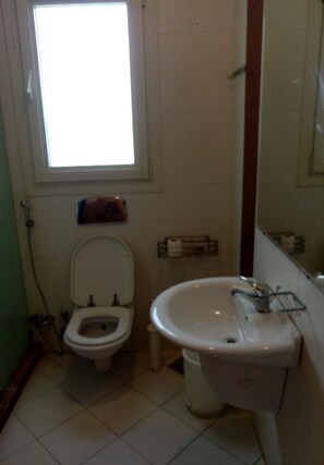 A small bathroom with a toilet, sink, and a window. - Villa Stand Alone Sea View Hacienda Bay (El Alamein)