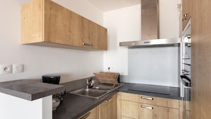 Une cuisine moderne avec des meubles en bois, une hotte en acier inoxydable et des appareils électroménagers intégrés.