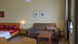 A room with a bed, a sofa, a small table, and a floor lamp. There are two framed pictures on the wall. - Vacation apartment in the heart of Berlin ( City West ) (Berlin)