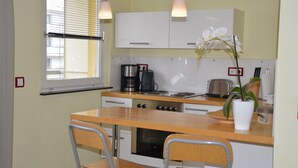 A compact kitchen with a wooden countertop, two chairs, a coffee maker, a toaster, and a potted orchid. - Vacation apartment in the heart of Berlin ( City West ) (Berlin)