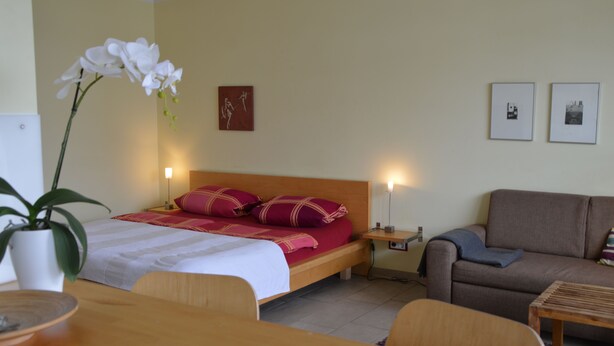 A bedroom with a bed, bedside tables, a nightstand, a sofa, a coffee table, and a potted plant. - Vacation apartment in the heart of Berlin ( City West ) (Berlin)