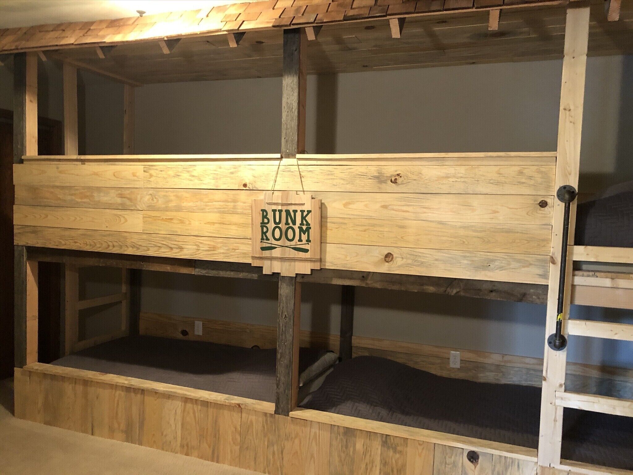 A bunk room with wooden bunk beds and a sign indicating it is a bunk room.
