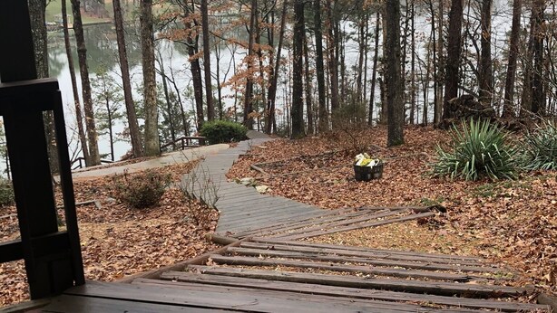 A wooden deck leading to a forested area with a lake. - Amazing Experiences Await Your Group - Family or Friends (Bella Vista)