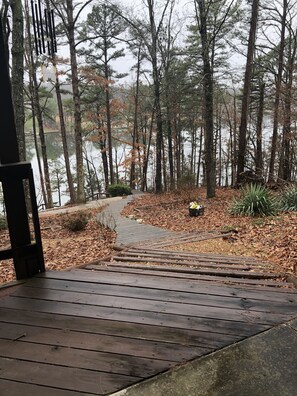 Une terrasse en bois qui mène à une zone boisée avec un lac.