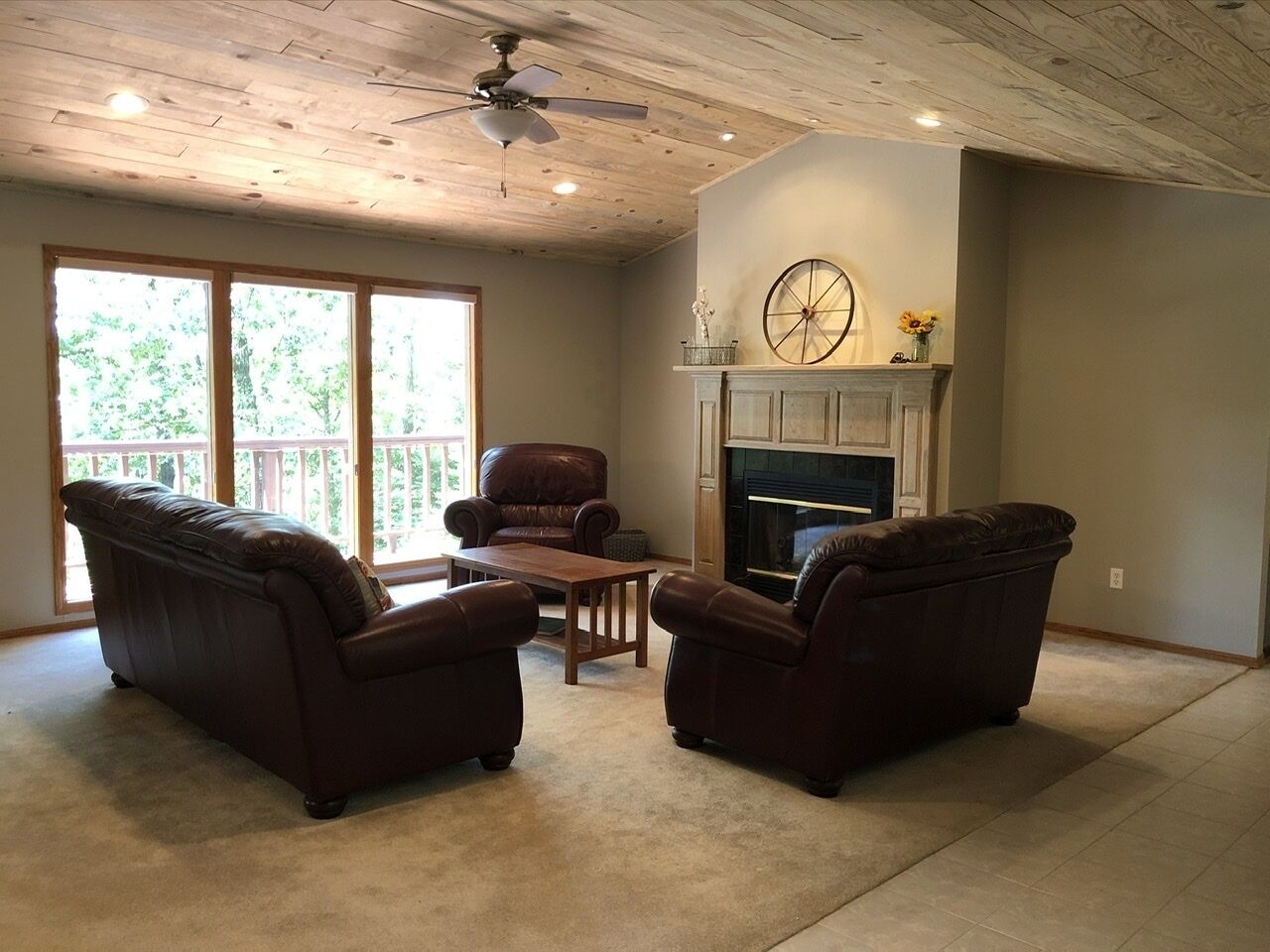 A living room with a fireplace, leather sofas, a wooden coffee table, and a ceiling fan.