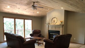 A living room with a fireplace, leather sofas, a wooden coffee table, and a ceiling fan. - Amazing Experiences Await Your Group - Family or Friends (Bella Vista)