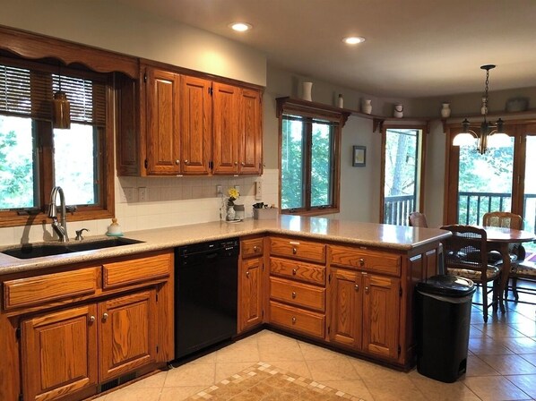 A kitchen with wooden cabinets, a dishwasher, and a large window.