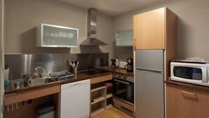 A compact kitchen with a dishwasher, oven, microwave, and a built-in stove. - Le Hameau du Comté de Foix (Mercus-Garrabet)