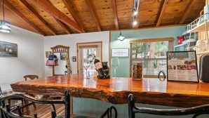 A rustic wooden bar area with a rustic wooden table, chairs, and a bear figurine. - JUST FOR 2!  NEAR ENTERTAINMENT/RESTAURANTS - HOT TUB - FIRE PIT - BBQ & A/C (Big Bear Lake)