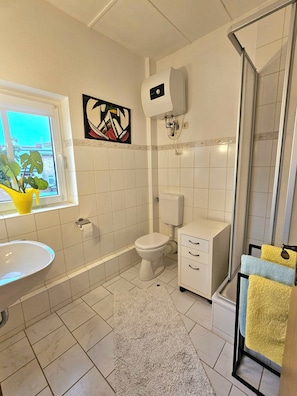 A bathroom with a toilet, sink, and shower area.