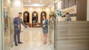 A hotel reception area with a modern interior, including a reception desk, a sofa, and a chandelier. - Momali Hotel Ninh Binh (Hoa Lu)