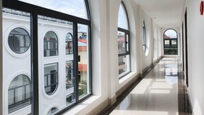 A corridor with large arched windows and a marble floor. - Momali Hotel Ninh Binh (Hoa Lu)