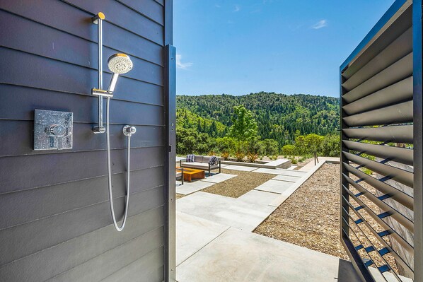 An outdoor shower area with a view of a forested hillside.