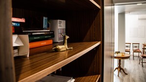 A wooden shelf with books, a decorative deer figurine, and a box labeled 'Cavalhossemagens.'