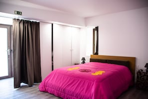 Une chambre d’hôtel avec un lit, une armoire, un miroir et une porte.
