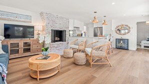 A modern living room with a fireplace, wicker furniture, and a flat-screen TV. - Balboa Island - Ruby Beach House
Steps from the beach. Sand in your toes. (Newport Beach)