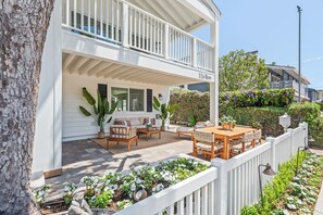 Une maison à deux étages dotée d’un balcon, d’un espace extérieur aménagé pour s’asseoir et d’un jardin bien entretenu.