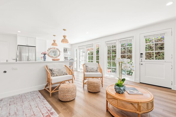 A bright room with wicker furniture, a round table, and a large window.