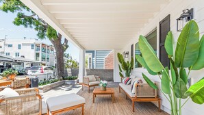 A covered outdoor seating area with wicker furniture, a coffee table, and large potted plants. - Balboa Island - Ruby Beach House
Steps from the beach. Sand in your toes. (Newport Beach)