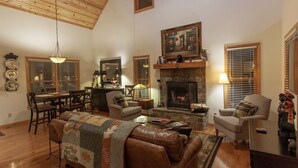 Una sala de estar acogedora con chimenea, techo de madera y un comedor con mesa y sillas.