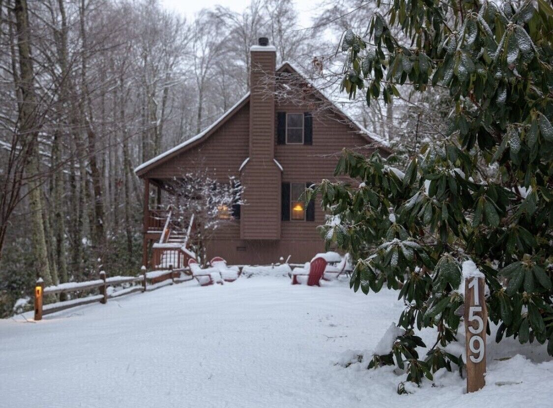 Une cabane avec une cheminée, une véranda et une cour enneigée.