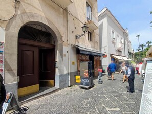 A street with a building featuring a large arched doorway and a signboard.