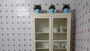 A small kitchen with a cabinet containing dishes and a coffee maker on the counter.