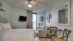 Ein Hotelzimmer mit Bett, Deckenventilator, Fernseher, Sofa, kleinem Tisch und Stühlen.