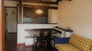 A compact living space with a kitchenette, a dining area, and a sofa. - Winter Holiday in Sestriere (Sestriere)