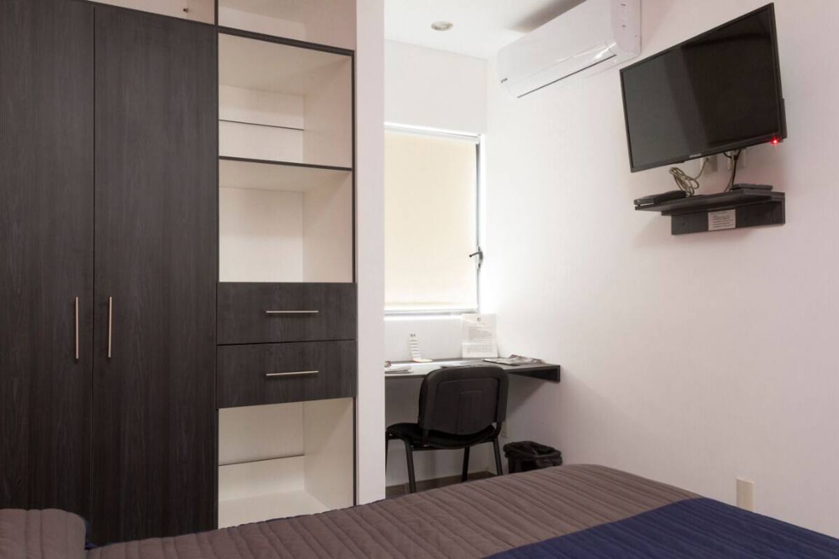 Edredón, muebles diferentes y espacio para trabajar con laptop