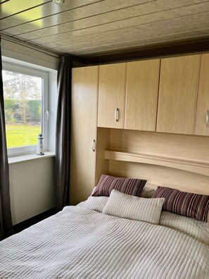 Una camera da letto con un letto grande, una testiera in legno e una finestra con tende.