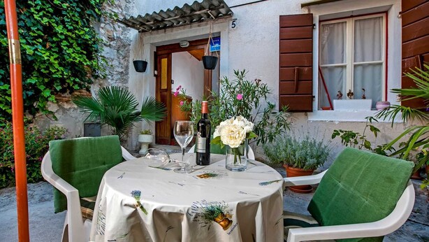 An outdoor patio with a round table set for two, surrounded by green chairs. - STELA - One Bedroom Apartment (Rovinj)