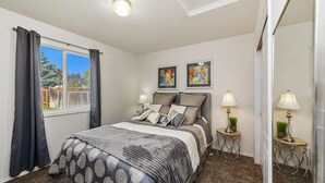 Un dormitorio con una cama grande, dos mesitas de noche con lámparas, y dos obras de arte enmarcadas en la pared.