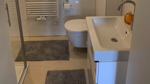 Een moderne badkamer met toilet, wastafel en douche.