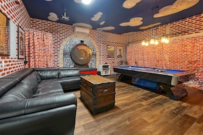 Ein Zimmer mit Backsteinwand, einer Poolbillardkugel, einem Ledersofa und einem Kamin.