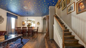 A dining area with a wooden table and chairs, a chandelier, and a starry ceiling.