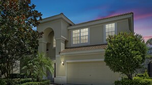 A two-story house with a garage, surrounded by well-maintained landscaping and a clear sky.
