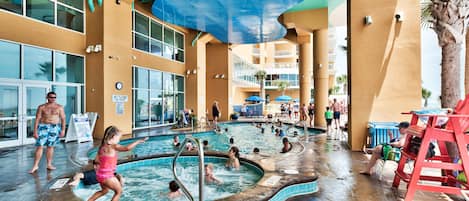 Een zwembadcomplex met meerdere zwembaden, een waterglijbaan en een badmeesterstandplaats.